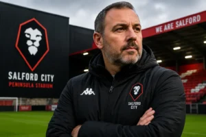 Peter Cklamovski Salford City manager poses with arms crossed at the Peninsula Stadium