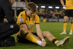 James Crole ankle injury sees Newport striker sit on the pitch clutching his bare foot as a member of staff attends to him during a match at Rodney Parade