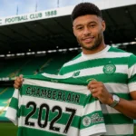 Oxlade-Chamberlain signs Celtic deal, holding a Celtic shirt with "Chamberlain 2027" at Celtic Park